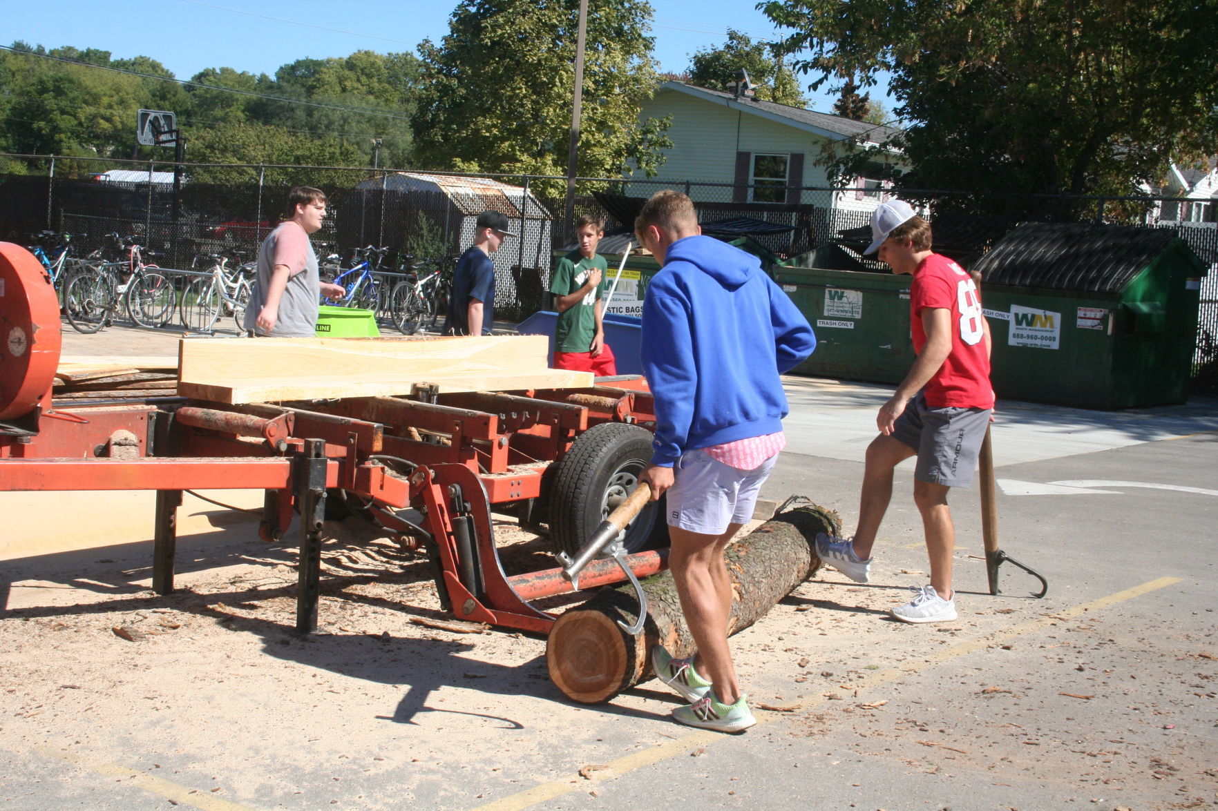 Students load tree trunk onto sawmill